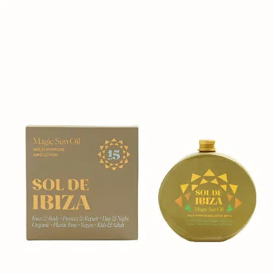 A bottle of Sol De Ibiza Magic Sun Oil, a multi-purpose zinc lotion with SPF 15 protection. The product is housed in a golden, circular container with eco-friendly packaging. The label emphasizes the organic, plastic-free, and vegan nature of the product, suitable for both face and body use. It is designed for day and night protection, catering to both kids and adults, while also offering repair and protection. The product is presented with a matching cardboard box.