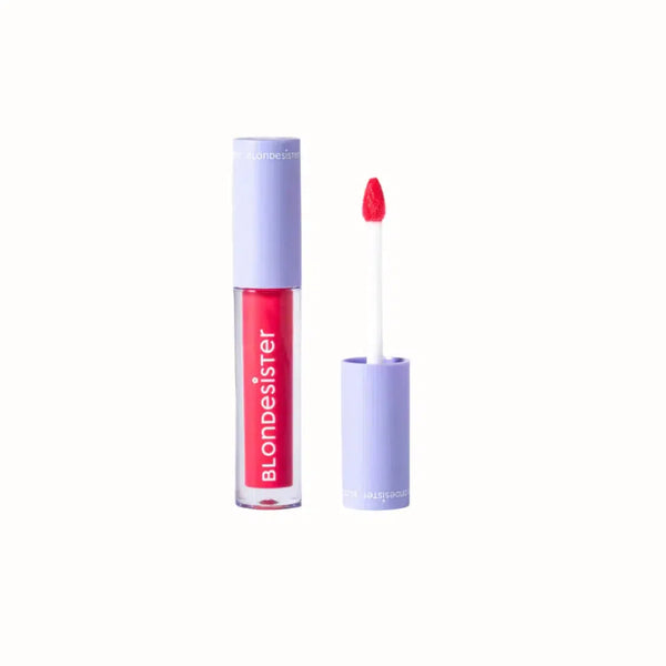 
A tube of Blondesister lip gloss featuring a vibrant red color. The packaging is sleek, with a purple cap and branding. The applicator is a pointed wand designed for precise application, delivering a high-shine finish. This lip gloss offers a bold, glossy look with smooth, comfortable wear.