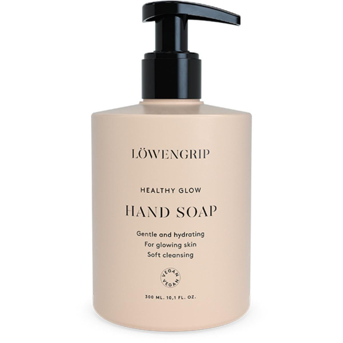 A sleek, minimalist bottle of Löwengrip Healthy Glow Hand Soap, featuring a clean, neutral-colored design. The pump bottle, with black accents, is labeled with the product name and key benefits such as "Gentle and hydrating" and "For glowing skin," promoting soft and nourishing cleansing. The packaging emphasizes its vegan-friendly formula, and the soap comes in a 300 ml size (10.1 fl. oz).