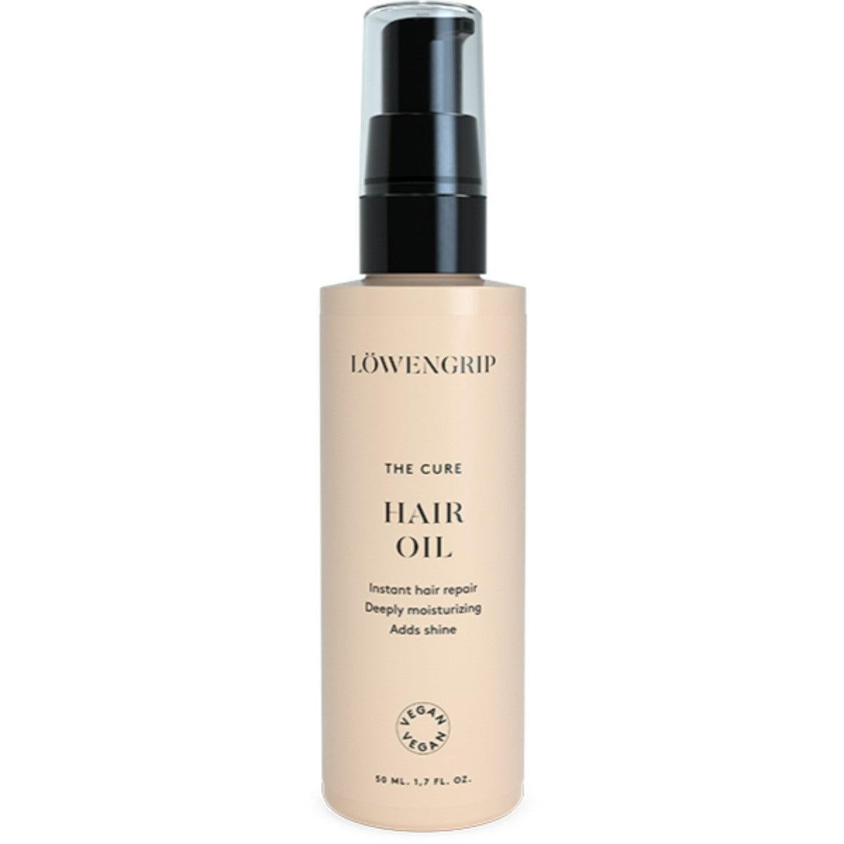 Löwengrip The Cure Hair Oil  
A bottle of Löwengrip The Cure Hair Oil featuring a pump dispenser. The product is labeled for instant hair repair, deep moisturizing, and adding shine. It comes in a soft beige bottle with black and gold detailing, indicating its vegan formulation. The bottle contains 50 mL (1.7 fl. oz.).